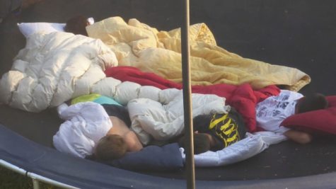 Kids sleeping together on a trampoline.