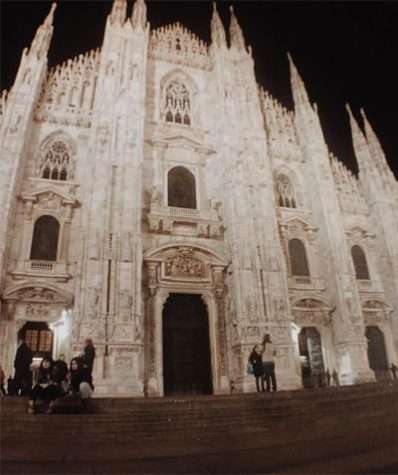 The Duomo Milano stands pale and white against the backdrop of the crisp, black winter night in Milan, Italy.