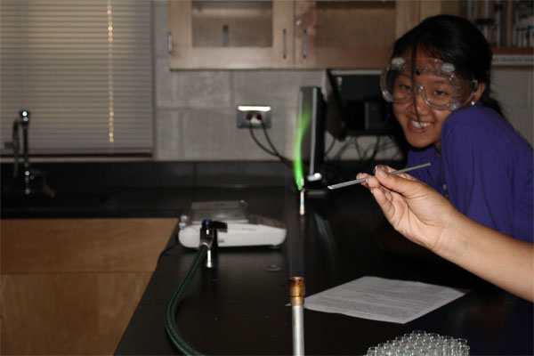 Senior Stephanie Tian cheerfully grins at the sight of  a fluorescent green flame. 