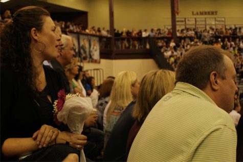 Parents of the homecoming court cheer their children on as they walk across the gymnasium.