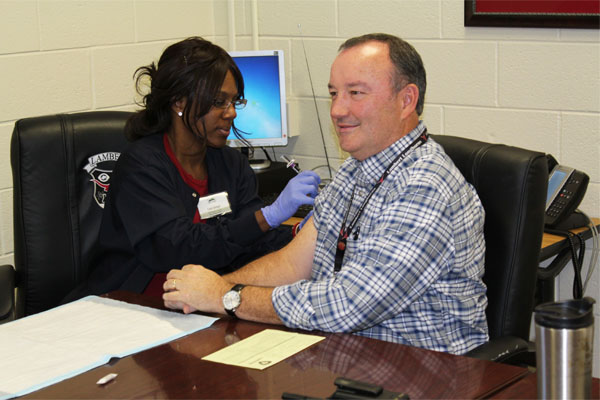 Nurse Conni Springer administers an immunization shot to one of Lamberts staff. 