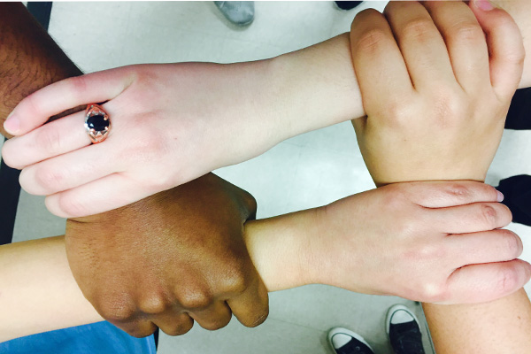 Lambert students of different backgrounds hold hands in unity.