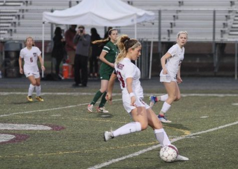 Maddie Eddleman kicks passes the ball ahead during a home game