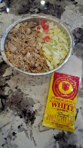 A chicken and rice platter from the Halal Guys with their signature tahini (white) sauce.