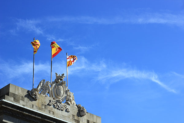 The Catalan Flag flying next to the Spanish Flag.   Photo by Blog Tyrant.   https://creativecommons.org/licenses/by-nc-sa/2.0/legalcode.   Link to original Work: https://www.flickr.com/photos/110466270@N03/11189167773/in/photolist-fYhX7Q-jfSr9J-jfSpR3-jfSu5o-i3KpKK-oZUHtE-5ryQVT-V6Uj7D-ph8wm8-jxsfbC-jfUCEN-jfSsW1-jxsgH5-ssjdo-phnDG3-jxqkYe-jxrxpr-jxsdN7-jxrrNg-jxqeeH-jxrk6Z-jxqdwa-jxqjjx-jxttqo-jxqraB-jxqfPM-jxrowr-jxsnZJ-jxryFV-oZVqQe-jxstko-jcLhnV-jcJoKa-jcL1W4-8nrR3t-ZaVjiQ-jcLa4B-jcNBLy-4uBqez-pAMAzY-73TYsn-25FiaP-2NArQ-YTgrzZ-xTgC3v-yP61DQ