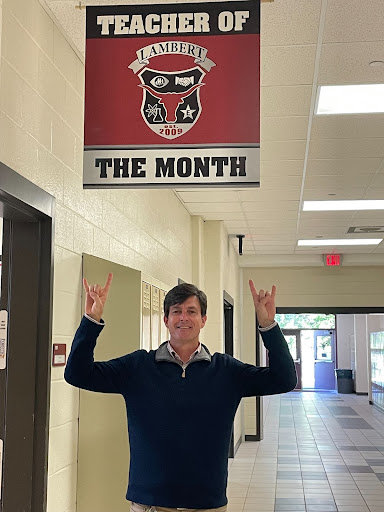 A photo of Mr. Wilson in front of his classroom with the teacher of the month award, Tuesday, November 2, 2021. (The Lambert Post/ Hunter Dzerve)
