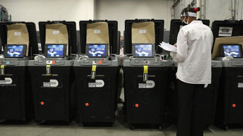A poll worker inspecting polling machines made by Dominion Voting Systems. Dominion has sued Fox News for defamation. (Ben Gray/AP)
