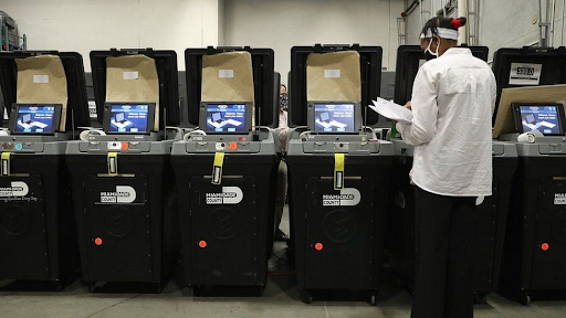 A poll worker inspecting polling machines made by Dominion Voting Systems. Dominion has sued Fox News for defamation. (Ben Gray/AP)

