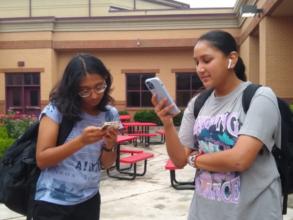 The image shows Freshman Naisha Sinha and Freshman Agamya Jain on their phones. Smartphones are a revolutionary piece of technology, but they can cause students to become distant. Eera Ingle/The Lambert Post