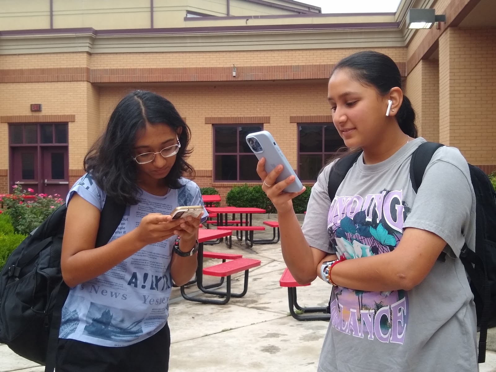 The image shows Freshman Naisha Sinha and Freshman Agamya Jain on their phones. Smartphones are a revolutionary piece of technology, but they can cause students to become distant. Eera Ingle/The Lambert Post