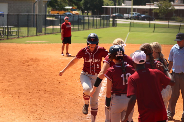 Avery Cole running into home and the team cheering her on. (Photo Credits Cade Studios)

